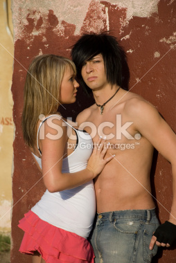 Teenage couple hugging against a wall