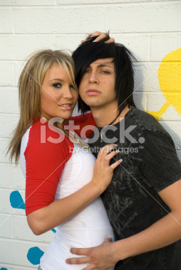 Teenage couple kissing in front of a grunge background