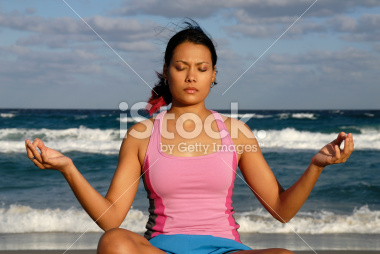 Latin american woman doing yoga on the beach